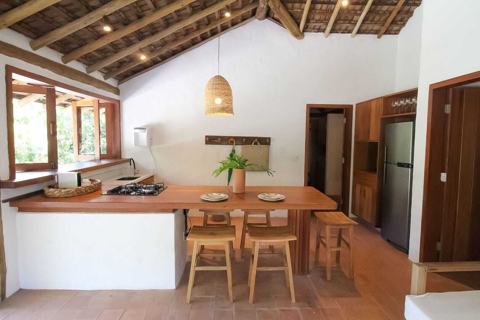 Cozinha com ilha de madeira, fogão a gás e luminária pendente.