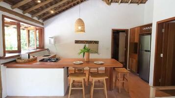 Cozinha com ilha de madeira, fogão a gás e luminária pendente.