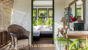 A room with a wooden ceiling, a wicker chair, a bed with a green frame, a table with a lamp, and a large mirror. - Pousada Outeiro (Porto Seguro)