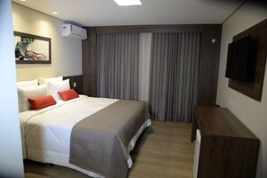 Una habitación de hotel con cama, escritorio, televisor y un cuadro en la pared.
