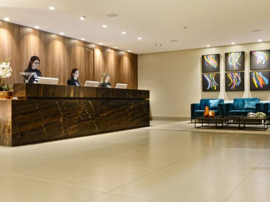 A reception area with a marble reception desk, three staff members, and a blue sofa set.