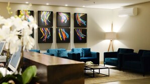 Un hall d’entrée moderne avec un comptoir d’accueil, des canapés bleus et des œuvres d’art abstraites accrochées aux murs.