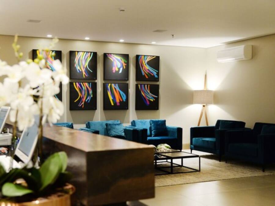 Un vestíbulo moderno con mostrador de recepción, sofás azules y arte abstracto en la pared.
