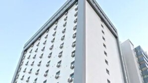 Un grand immeuble abritant un hôtel, avec de nombreux étages, des unités de climatisation et un restaurant appelé « The Collection » situé au rez-de-chaussée.