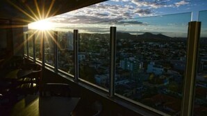 Une pièce dotée d’une grande fenêtre donnant sur un paysage urbain au coucher du soleil.