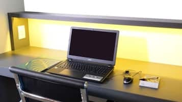 Una computadora portátil sobre un escritorio, con una silla al frente.