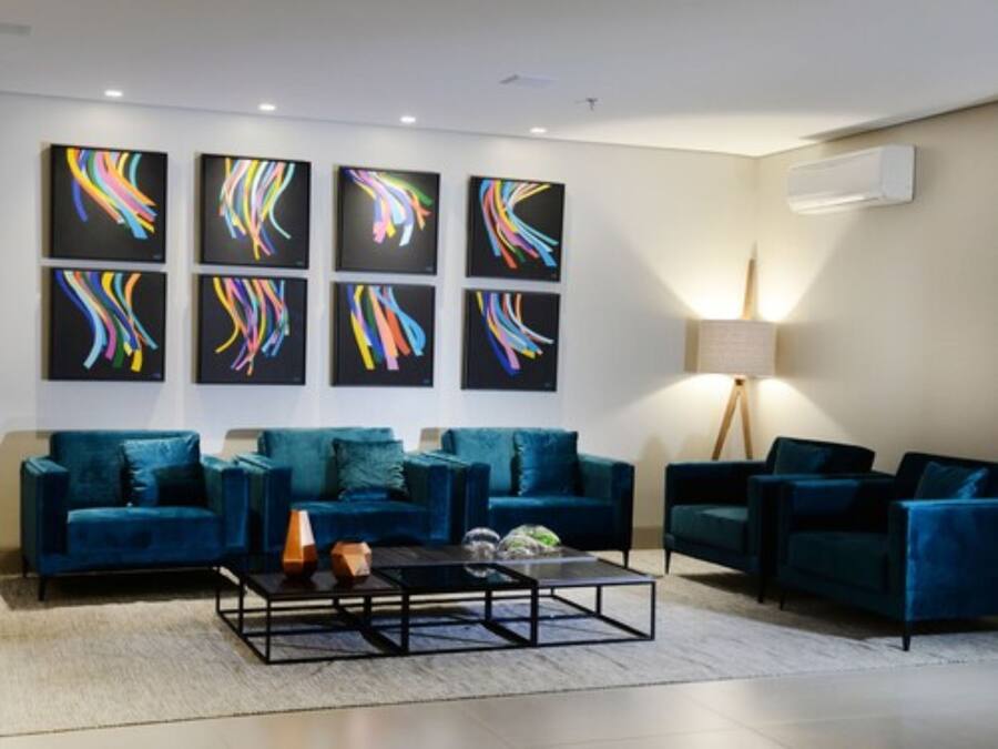 Een moderne woonkamer met smaragdgroene banken, een bijzettafeltje en abstracte kunst aan de muur.