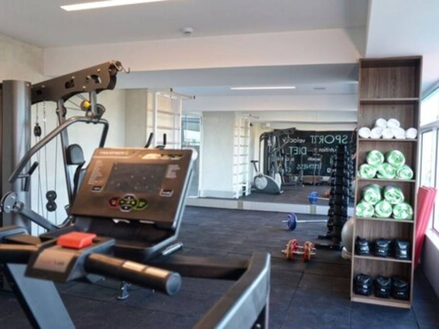 A gym with cardio equipment, weightlifting racks, and a mirror.