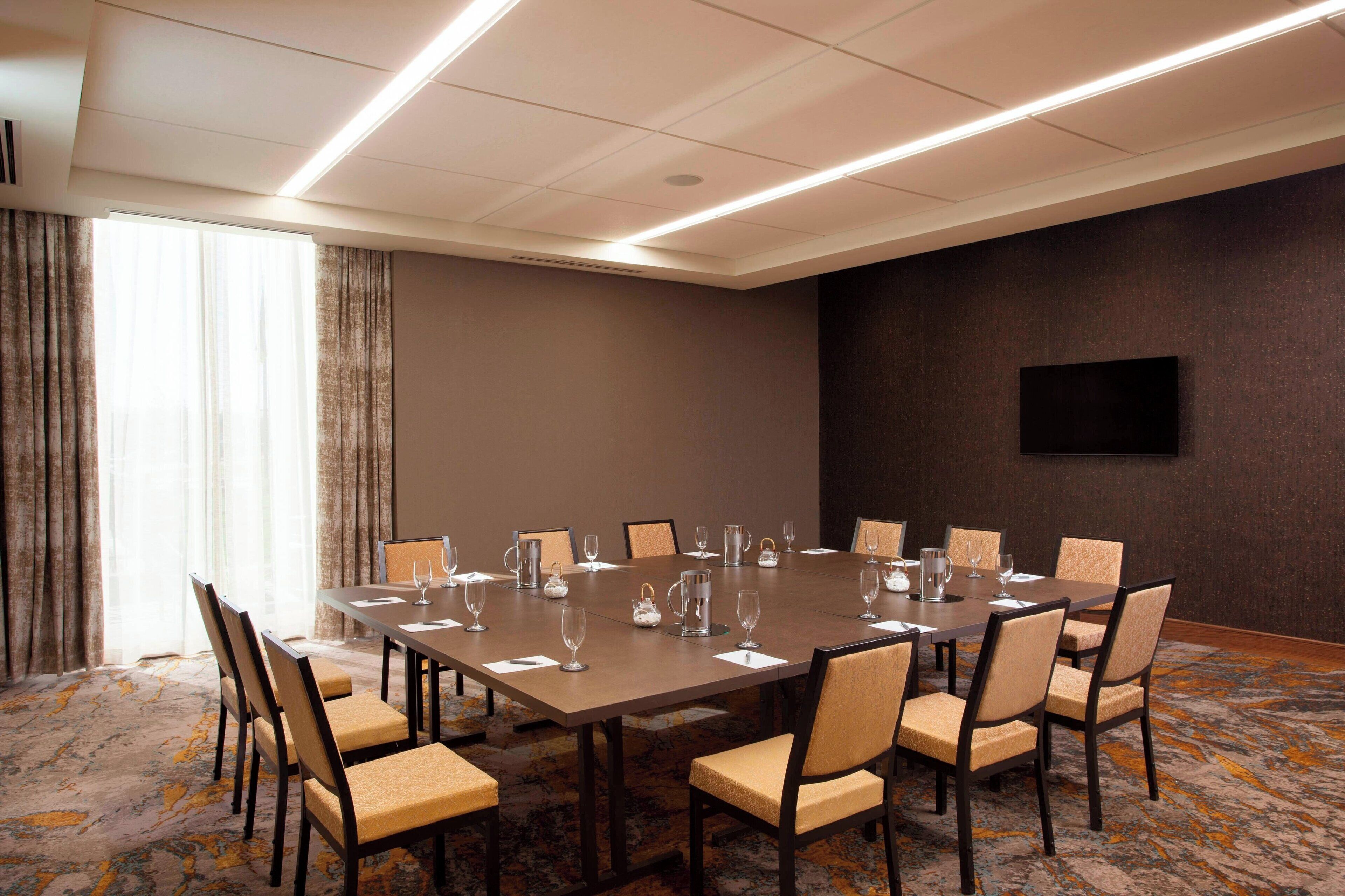 A conference room with a large table, chairs, and a flat-screen TV on the wall.