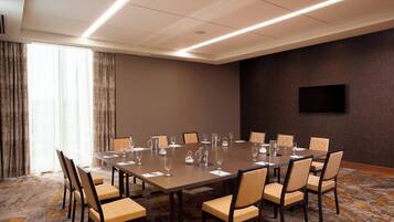 A conference room with a large table, chairs, and a flat-screen TV on the wall.