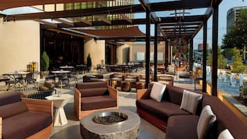 An outdoor lounge area with sofas, tables, and a fire pit.