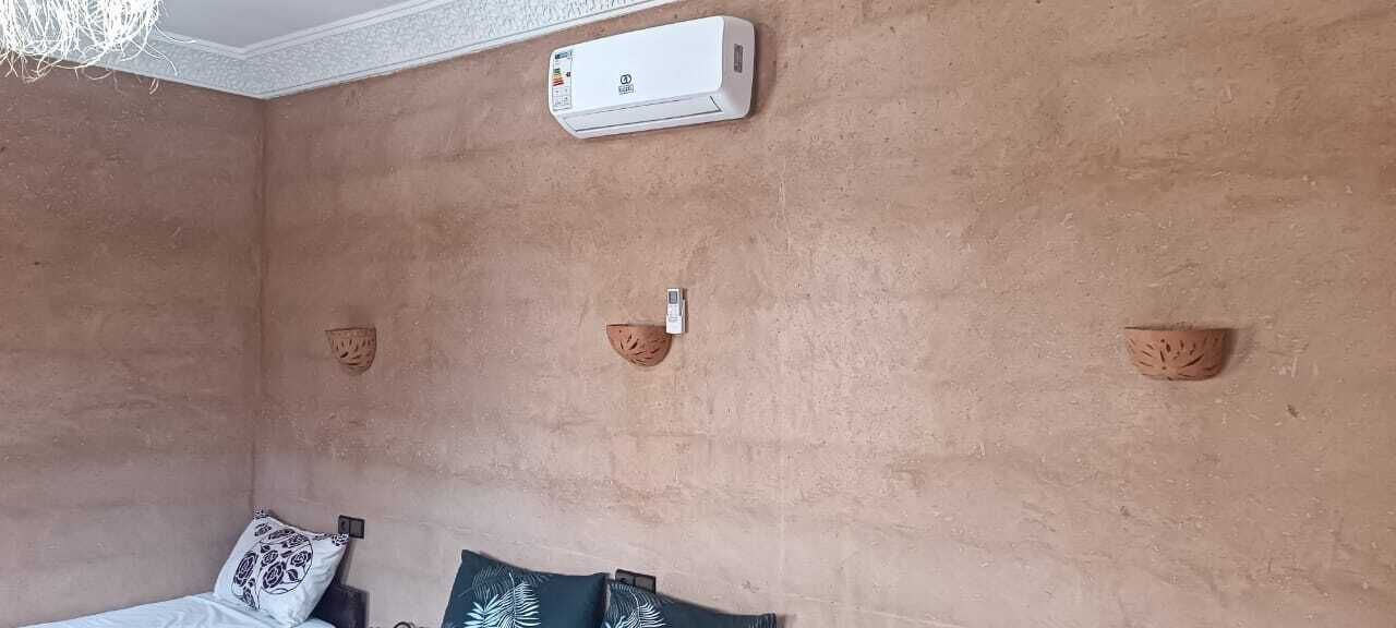 Une chambre avec un lit, un climatiseur fixé au mur et des appliques murales décoratives.