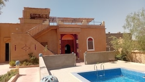Un bâtiment doté d’une piscine, d’un escalier et d’une porte surmontée d’une arche rouge.