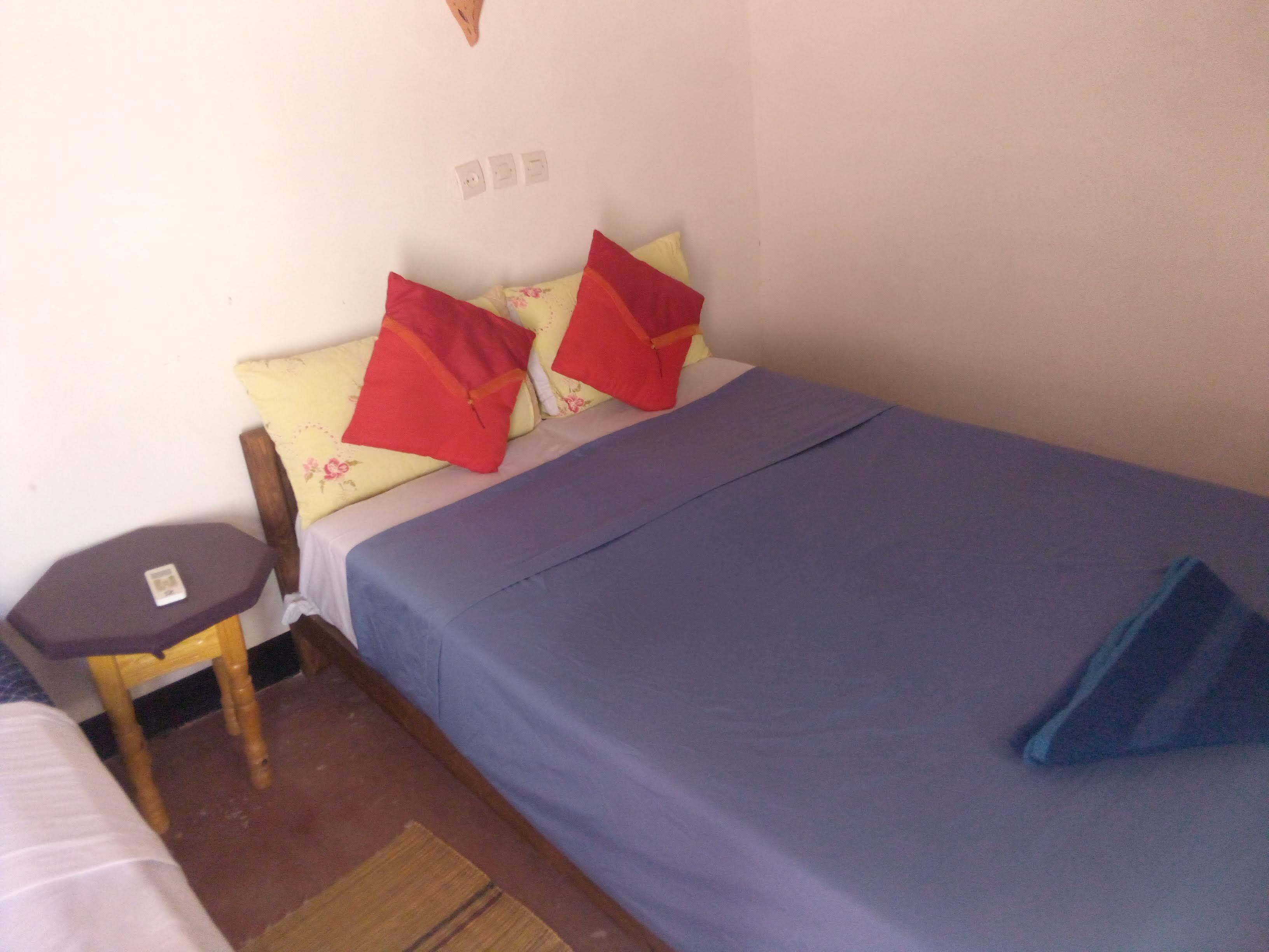 A small, simple room with a single bed, a small table, and a chair.