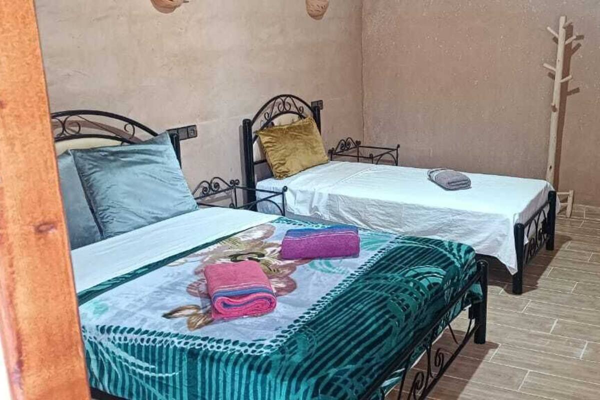 Ein kleines, gemütliches Zimmer mit zwei Einzelbetten, einem kleinen Tisch und einem Stuhl.
