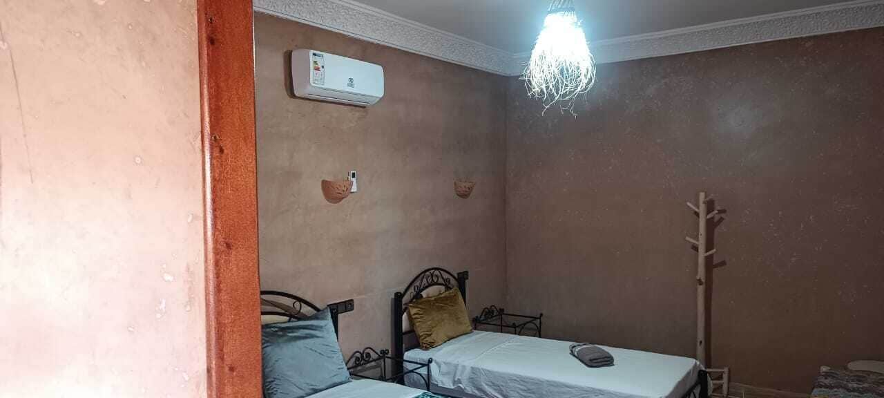 Una camera da letto piccola con due letti, un termosifone a parete e un attaccapanni.
