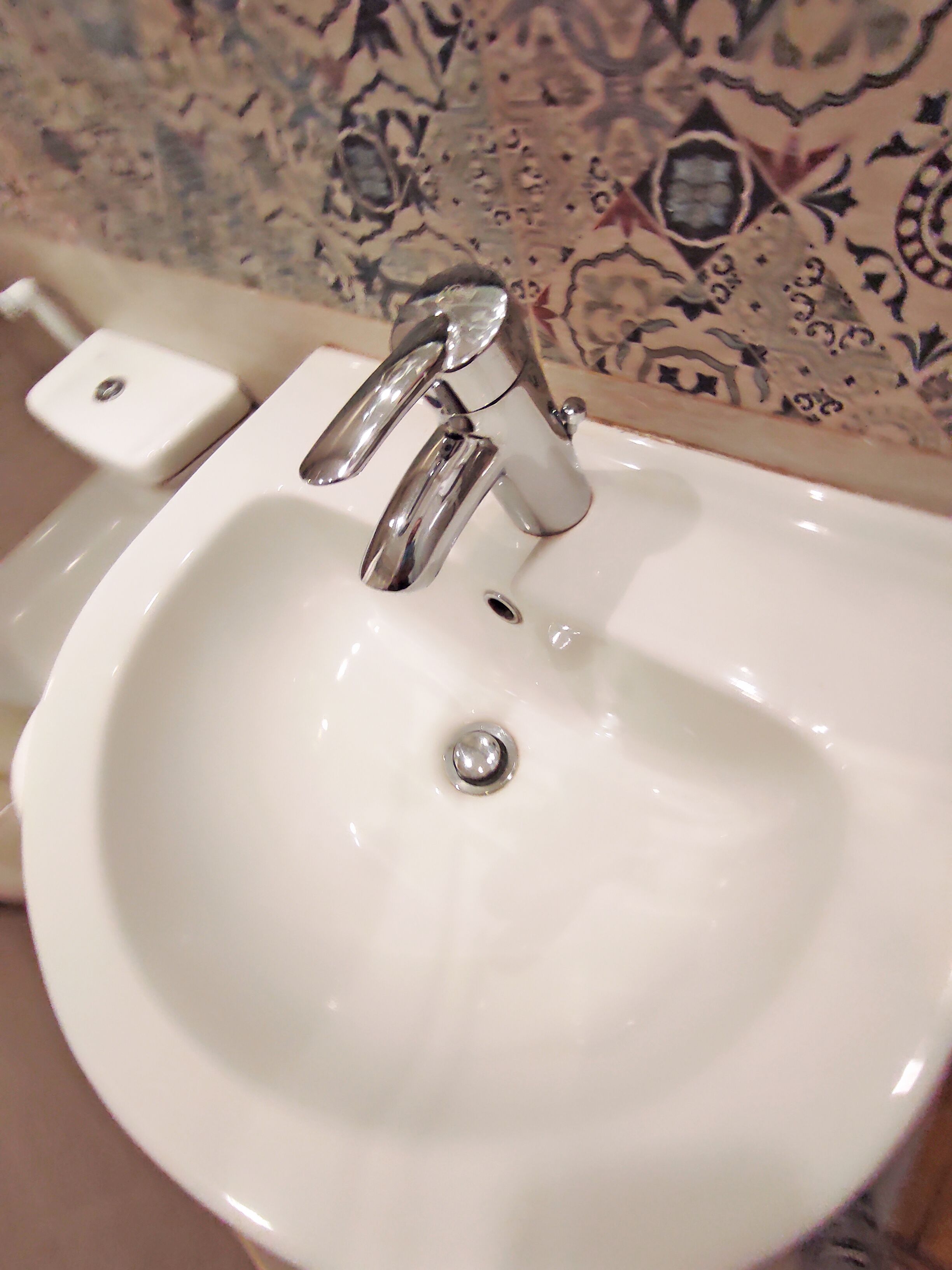 A white bathroom sink with a chrome faucet and a single drain.