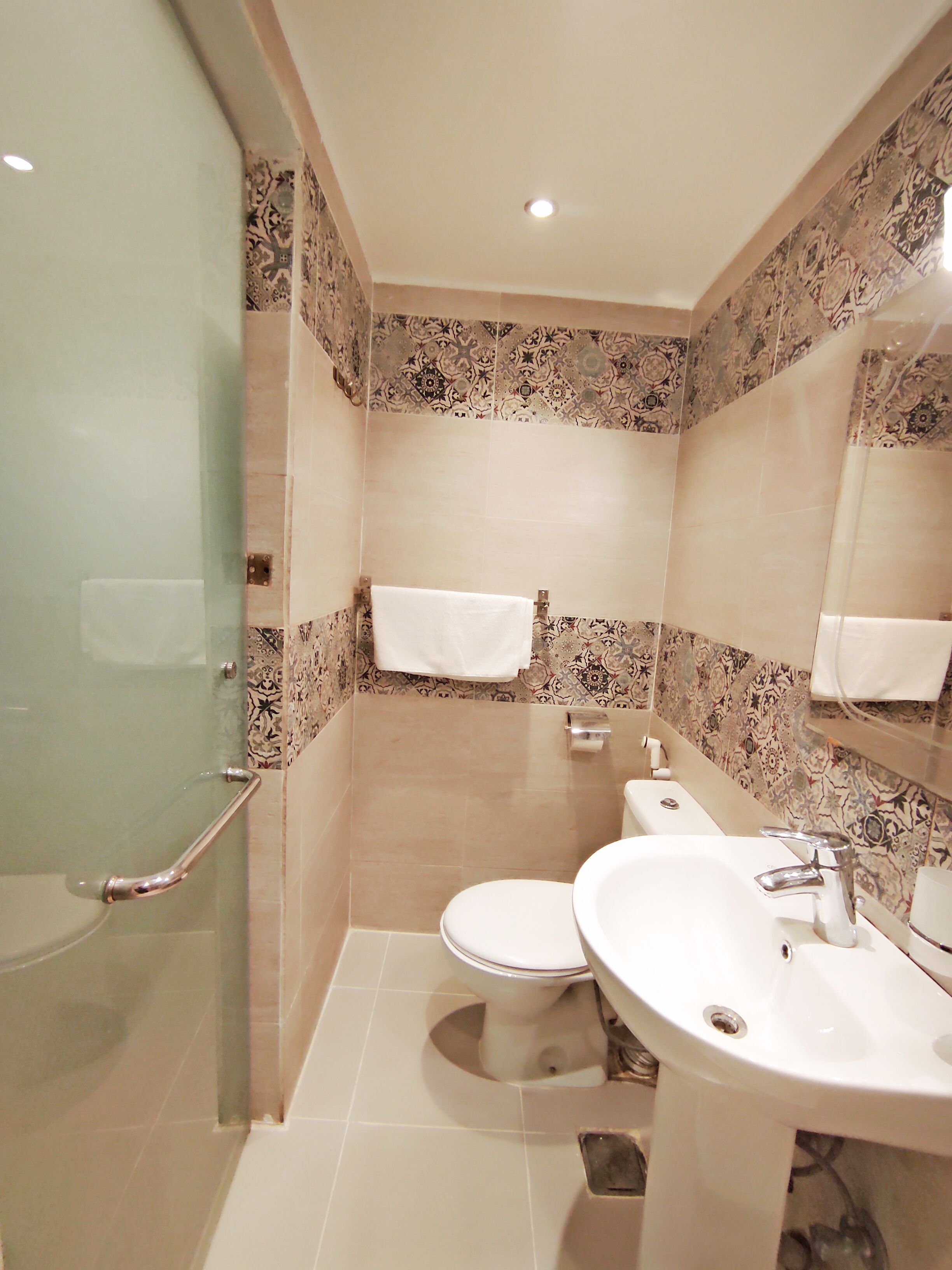 Ein modernes Badezimmer mit Duschkabine aus Glas, einer weißen Toilette und einem Waschbecken mit Spiegel darüber.