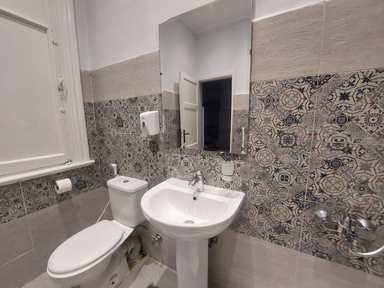 A bathroom with a toilet, sink, and mirror.