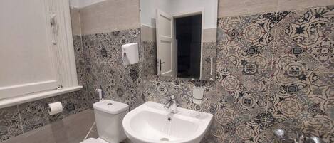 A bathroom with a toilet, sink, and mirror.