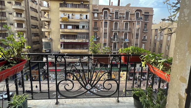 A balcony with potted plants, overlooking a street with various buildings, including a hotel. - Sufi House (Cairo)