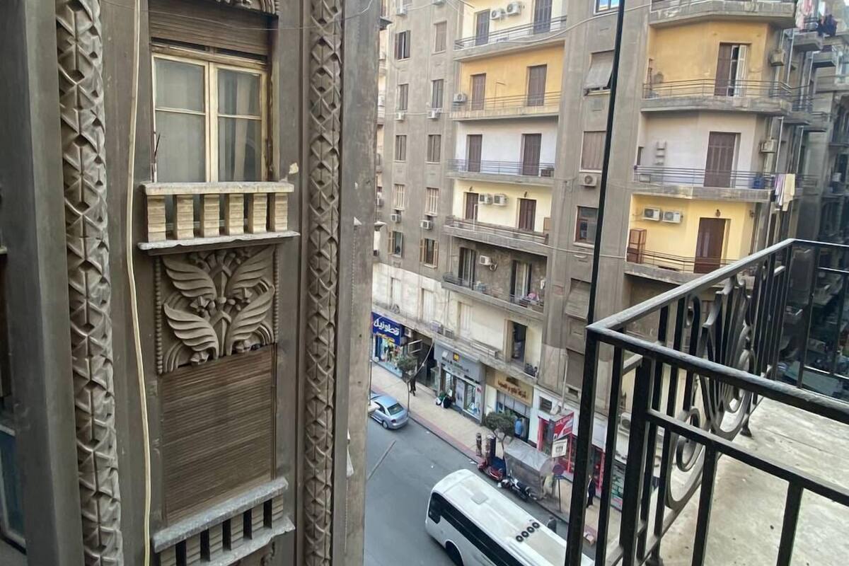 Un edificio de varios pisos con detalles arquitectónicos ornamentales, incluyendo patrones de hojas esculpidas y barandilla de balcón.