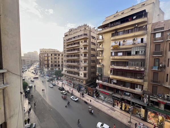 A multi-story hotel with balconies, a street view, and various shops.
