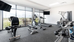 A gym with exercise equipment, a treadmill, and a TV screen. - Park Inn by Radisson Edmonton Airport (Leduc)