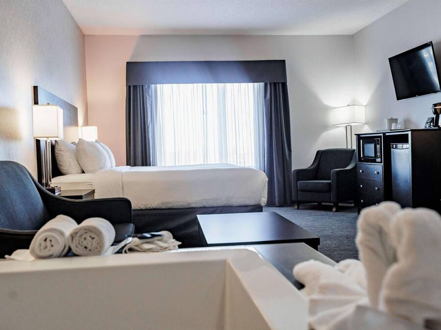 Quarto de hotel com cama, escrivaninha, televisão e móvel de televisão com micro-ondas.