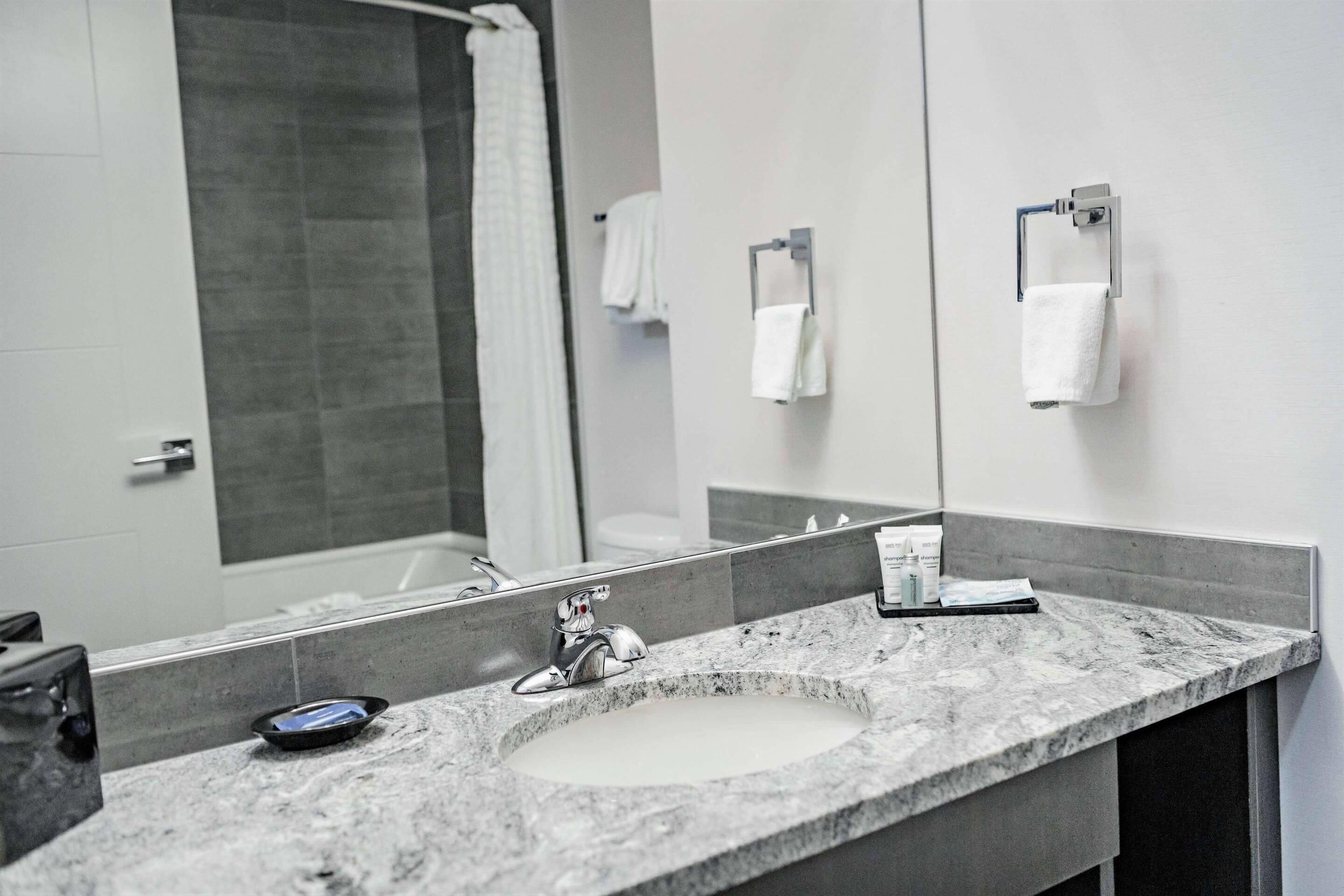 A bathroom with a large mirror, a sink, and a shower area.