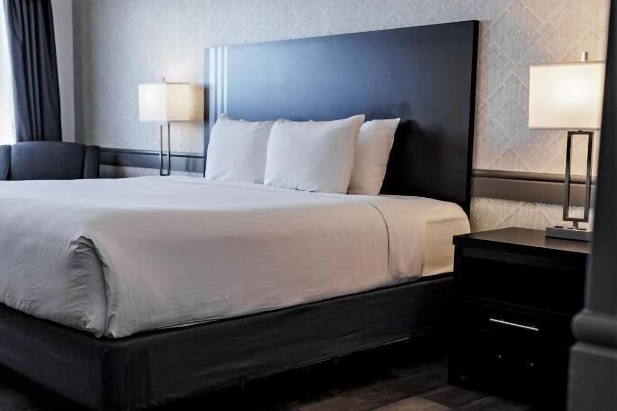A hotel room with a large bed, bedside tables, and lamps.