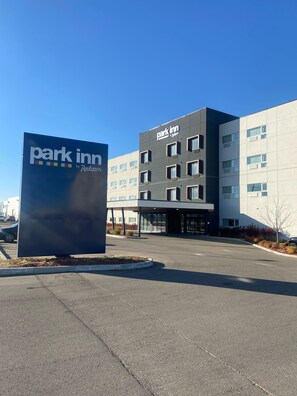 A modern building with a 'Park Inn by Radisson' sign, featuring a flat facade with multiple windows and a covered entrance.