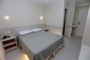 A hotel room with a bed, bedside table, and a wardrobe.