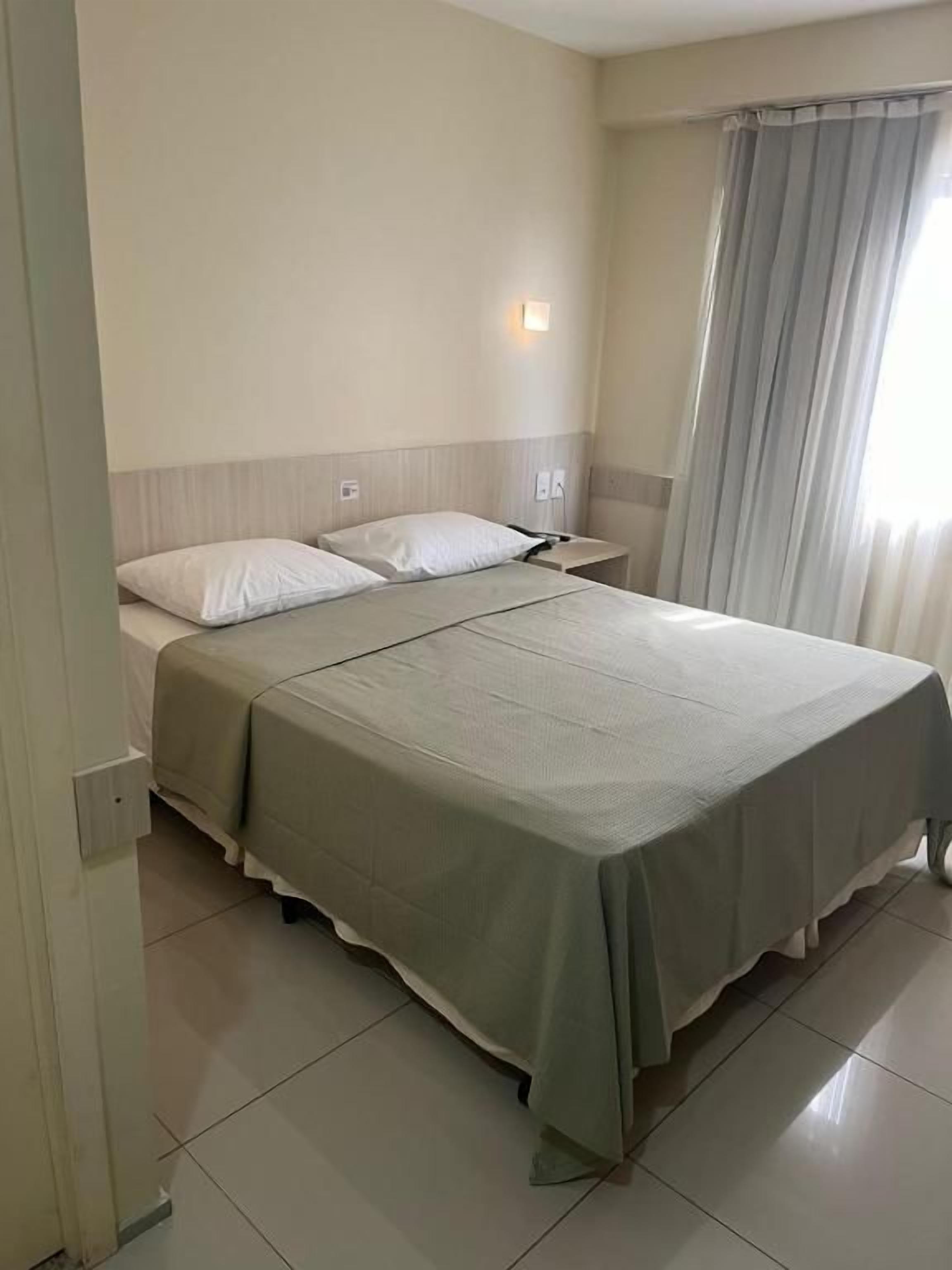 Une chambre d’hôtel avec un lit, des tables de chevet et une fenêtre avec des rideaux.