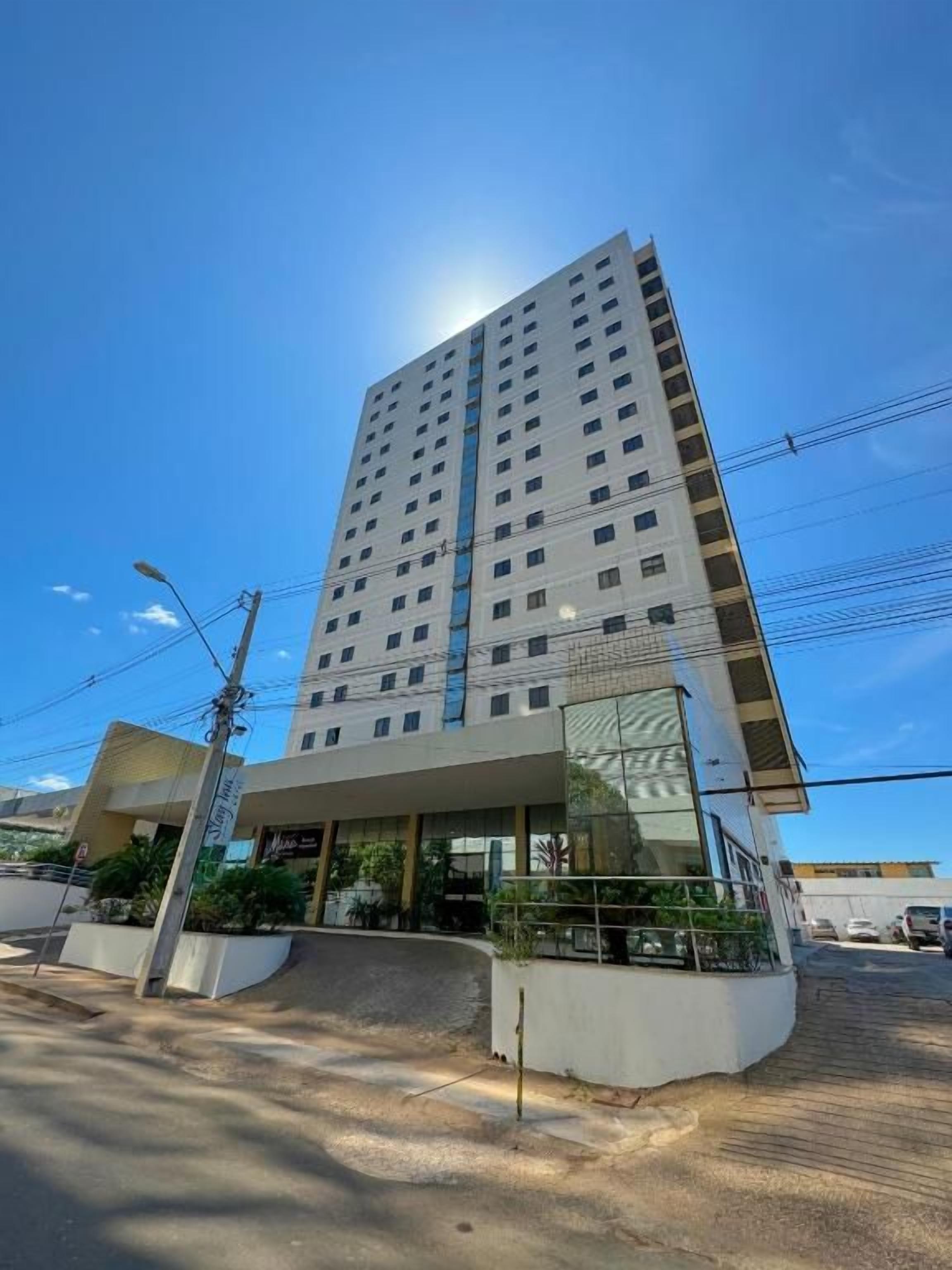 Un immeuble de grande hauteur au design moderne, doté d’une entrée imposante et offrant une vue dégagée sur le ciel.
