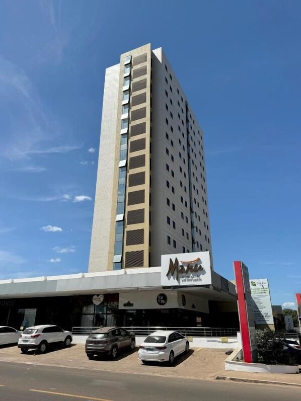 A tall hotel building with a modern design, featuring a prominent logo on the facade.