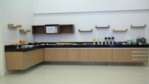 A modern kitchen with wooden cabinets, a black countertop, and various kitchen appliances. - Stay Inn Hotel (Imperatriz)