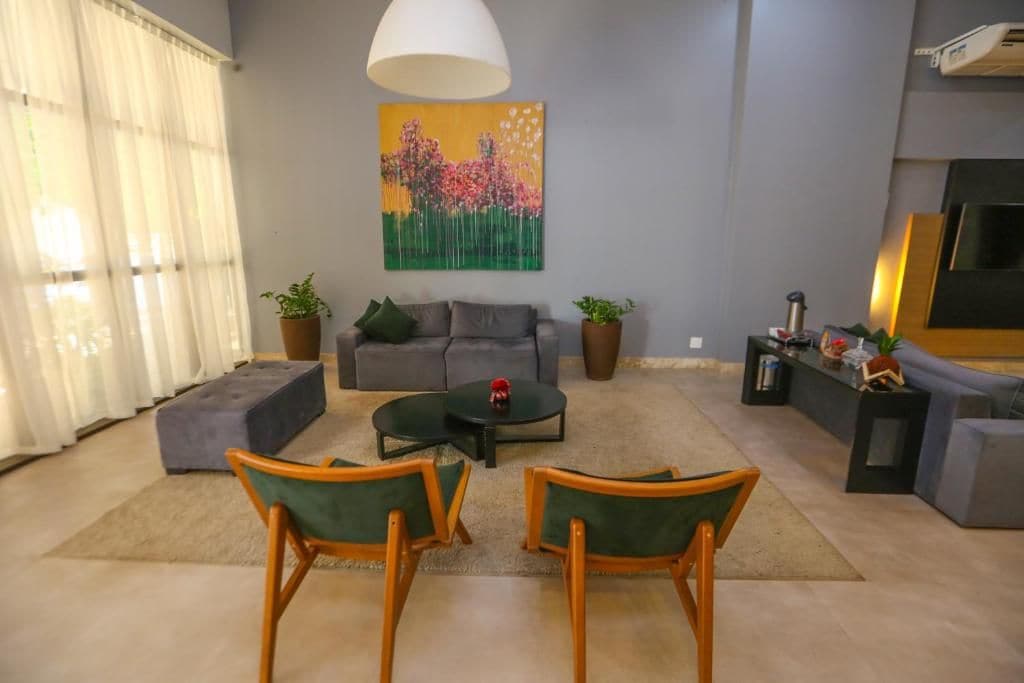 Una sala de estar con un sofá gris, dos sillones, una mesita de centro y un cuadro en la pared.