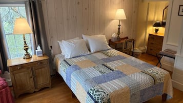 Un dormitorio con una cama grande, dos mesitas de noche con lámparas, un aparador y una ventana con cortinas.