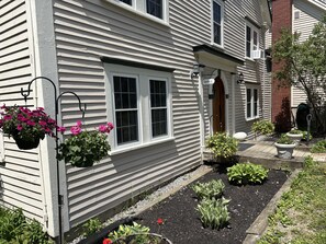 A house with a front porch, potted plants, and a garden bed.
