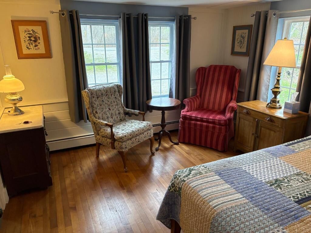 Una habitación con cama, una silla, una mesa y una lámpara.