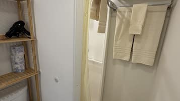 Un baño compacto con inodoro, zona de ducha y toallero con toallas ordenadamente dobladas.
