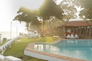 Una piscina al aire libre, sombrillas, sillones reclinables de piscina