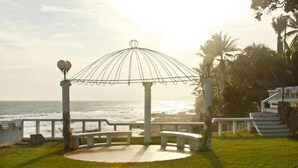 A gazebo with a view of the ocean, surrounded by a grassy area and palm trees. - Quinta MonteCarlo (La Libertad)