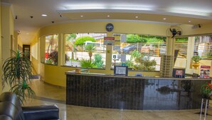 Zona de recepción con mostrador, un reloj y vistas al exterior.