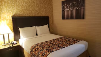 Een hotelkamer met een bed, een nachtkastje met een lamp, een telefoon en een stadslandschap schilderij aan de muur.