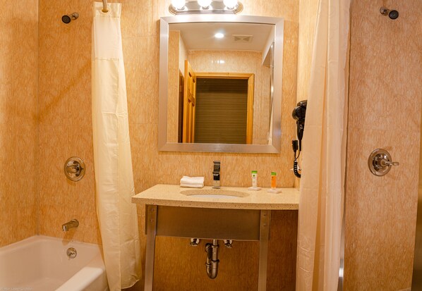 A bathroom with a sink, mirror, and shower.