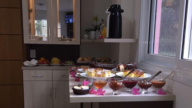 Eine Küche mit Esstisch, gedeckt für ein Frühstück, einschließlich Gebäck, Früchten und Getränken.