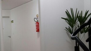 Ein Korridor mit Holzboden, weißen Wänden, einem roten Feuerlöscher und einem Topfpflanzen.