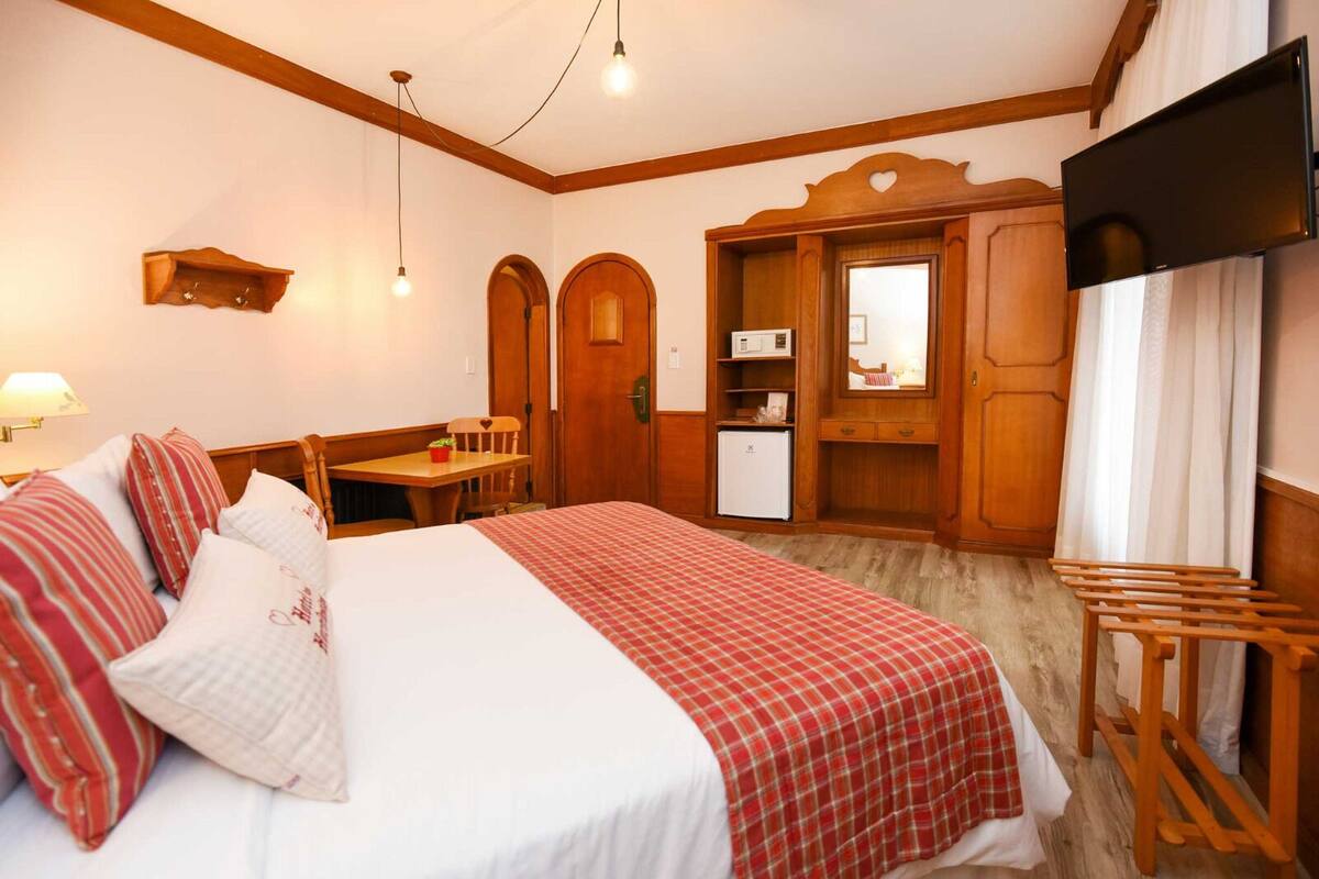 Una habitación de hotel con cama, escritorio, televisión y armario.